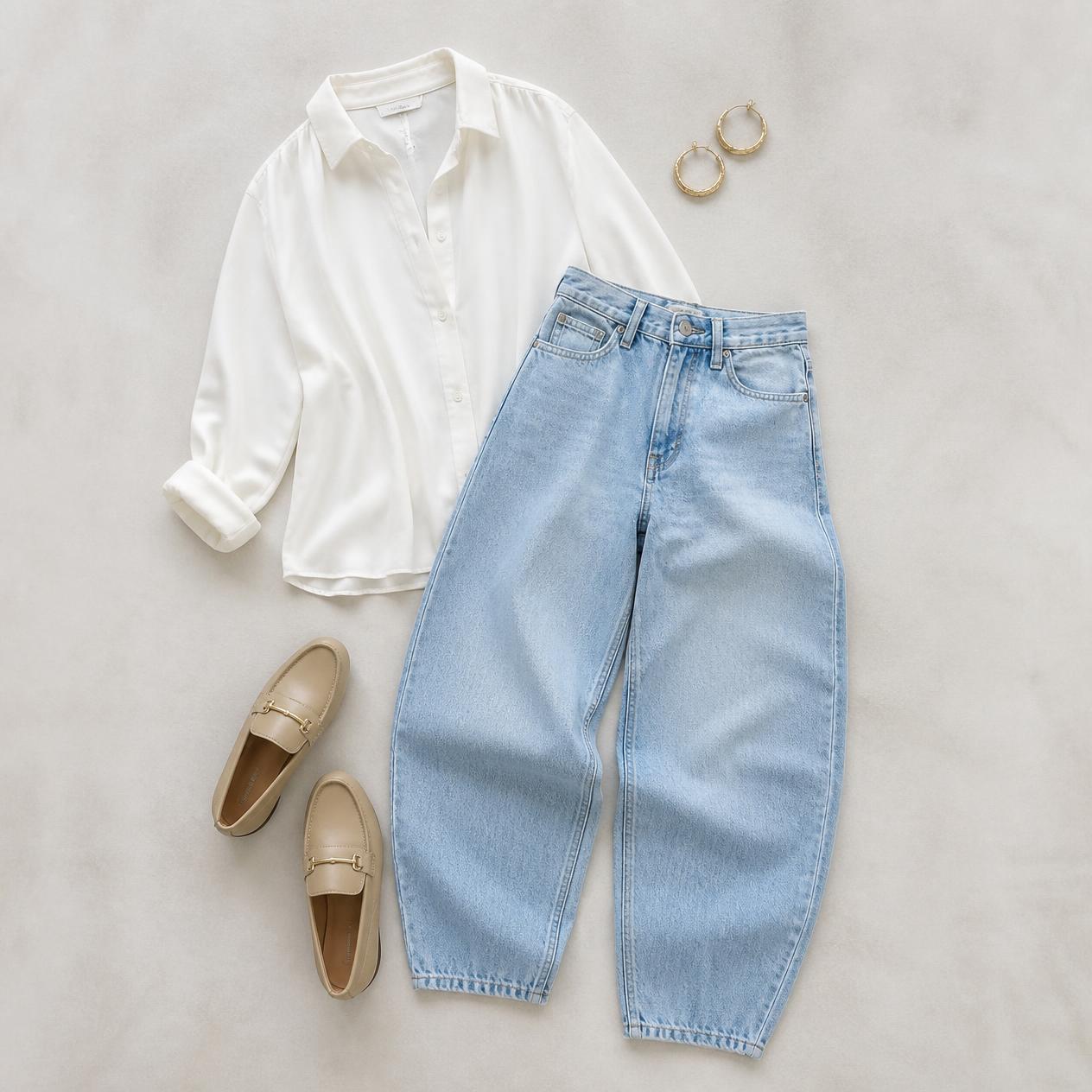 Overhead flatlay photo of light-wash barrel jeans styled with a white blouse and loafers