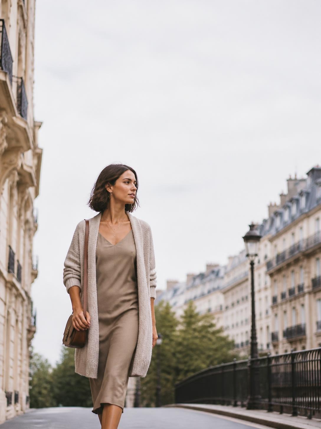 Woman in a neutral midi dress and oatmeal cardigan walking on a Paris street